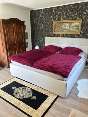 A bed with a white headboard, a dark patterned wall, a framed picture, and a wooden wardrobe. - Newly renovated—modern vacation home near the North Sea (Rehm-Flehde-Bargen)