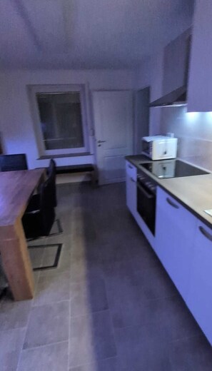 A compact kitchen with a dining table, a window, and a door. - Newly renovated—modern vacation home near the North Sea (Rehm-Flehde-Bargen)