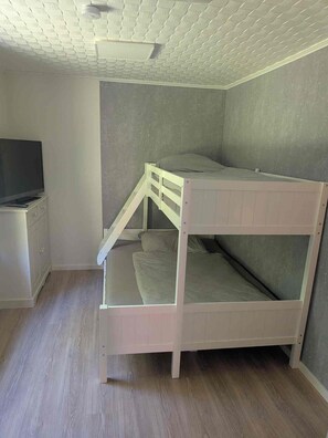 A bunk bed in a room with a television on a stand, a cabinet, and a ceiling with a grid pattern. - Newly renovated—modern vacation home near the North Sea (Rehm-Flehde-Bargen)