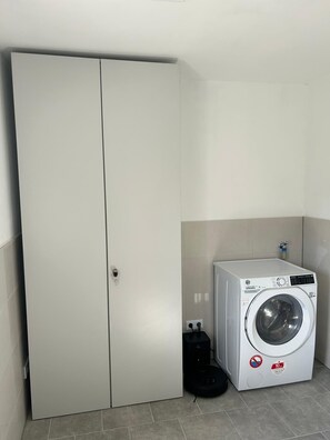 A compact laundry room with a washing machine, a dryer, and a tall wardrobe. - Newly renovated—modern vacation home near the North Sea (Rehm-Flehde-Bargen)