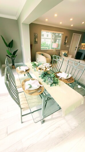 A dining area with a glass table set for six, surrounded by chairs. - Beautiful waterfront condo with stunning views of Mooring Bay (Naples)
