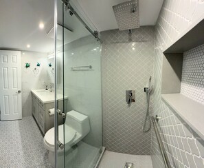 A modern bathroom with a glass-enclosed shower, a toilet, and a sink. - Beautiful waterfront condo with stunning views of Mooring Bay (Naples)