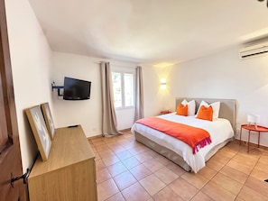 A bedroom with a bed, a TV mounted on the wall, a desk, and a small table with a lamp. - Villa Océane. Spacious House with Swimming Pool – Pernes-les-Fontaines (Pernes-les-Fontaines)