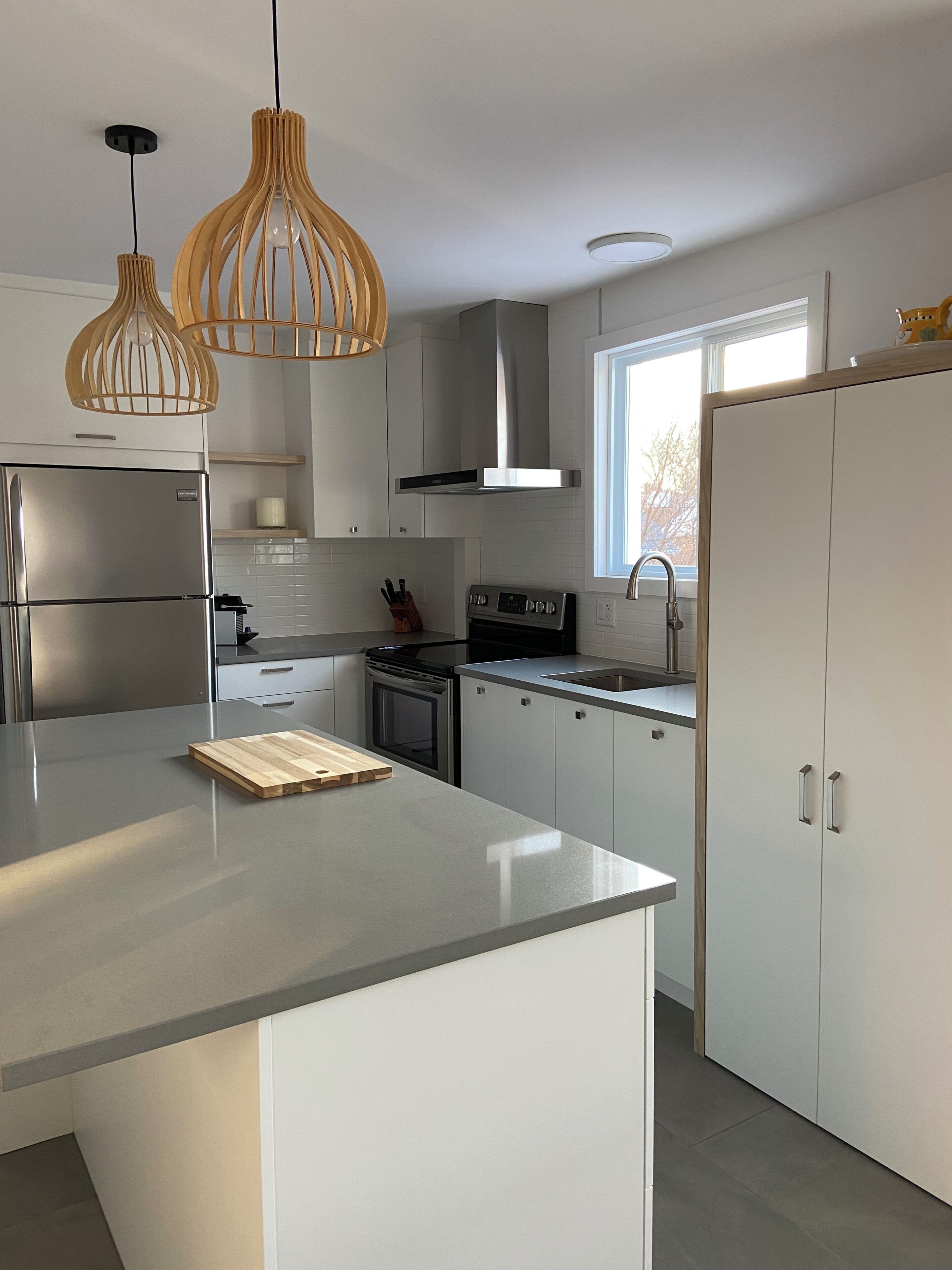 A modern kitchen with a central island, stainless steel appliances, and pendant lighting.