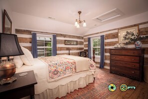 Een slaapkamer met een groot bed, een dressoir, een nachtkastje, een lamp en een plafondlamp.
