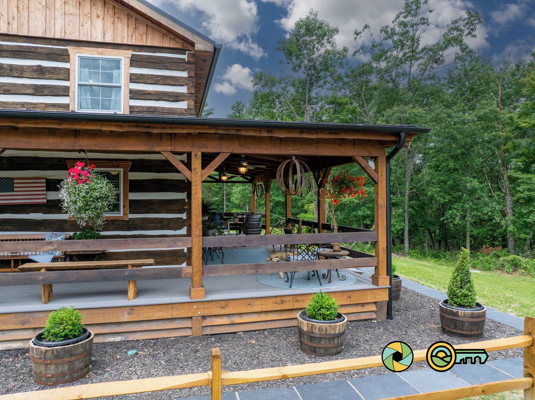 A rustic wooden cabin with a covered porch, outdoor seating, and potted plants.