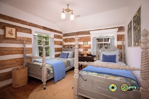A room with two wooden beds, a woven basket, and a chandelier.