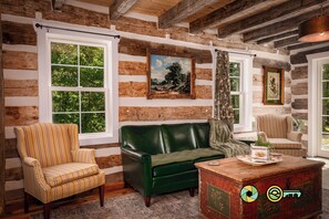 Een rustiek chaletinterieur met een gestreept fauteuil, een groene bank en een houten salontafel.