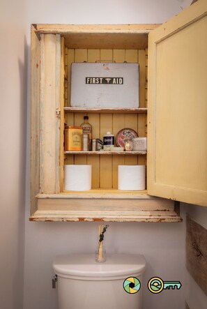 A wooden cabinet with a 'FIRST AID' label, containing items like a bottle, a tin, and a soap bar. - The Sawmill Inn - pre-Civil War luxury log cabin on 70+ private acres! (Mount Jackson)