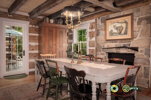 A rustic dining room with a large wooden table, chairs, and a chandelier. - The Sawmill Inn - pre-Civil War luxury log cabin on 70+ private acres! (Mount Jackson)