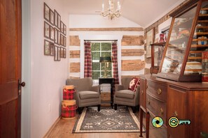 A cozy room with a sofa, armchairs, a patterned rug, a wooden cabinet, and a window with curtains. - The Sawmill Inn - pre-Civil War luxury log cabin on 70+ private acres! (Mount Jackson)