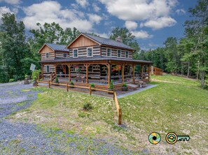 A log cabin with a porch, a covered outdoor seating area, and a gravel driveway. - The Sawmill Inn - pre-Civil War luxury log cabin on 70+ private acres! (Mount Jackson)