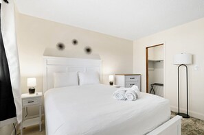 Ein Hotelzimmer mit einem großen Bett, einem Nachttisch mit Lampe, einem Schrank und einer Stehlampe.