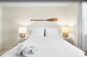 Ein Hotelzimmer mit einem großen Bett, zwei Nachttischlampen und einem an der Wand befestigten Baseballschläger.