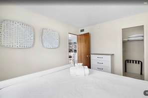 A bedroom with a bed, a wardrobe, a chair, and a door leading to a bathroom. - Snyder's Rest - B managed by Beach Retreats FL (Bradenton Beach)
