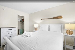 Une chambre d’hôtel comprenant un lit, une table de chevet avec une lampe, une commode et un placard.