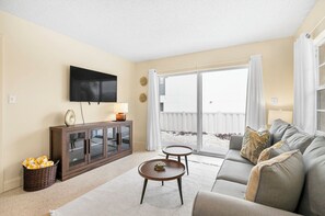 Ein Wohnzimmer mit einer Couch, einem Fernseher, einem Schrank und einer Schiebetür zu einem Außenbereich.