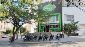 Un edificio con fachada verde y blanca, un letrero que dice 'Caru', y varias motocicletas estacionadas en la entrada.