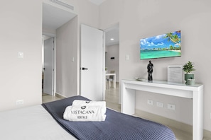 Ein Hotelzimmer mit Bett, Schreibtisch mit Fernseher und Blick auf einen Strand.