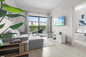 A modern living room with a sofa, coffee table, and a TV mounted on the wall. - NOK Stylish 1BR in Ventura By Vistacana (Punta Cana)