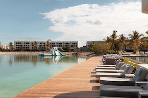 Ein Hotelpool mit Liegestühlen, einer Holzterrasse und einem Gebäude im Hintergrund.
