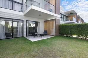 Un immeuble résidentiel moderne à deux étages, doté d’un patio couvert, de grandes fenêtres et d’une pelouse bien entretenue.