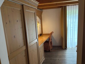 A room with wooden cabinets, a wooden bench, and a window with curtains. - Double or Twin Room with Private Bathroom (Mestriago)