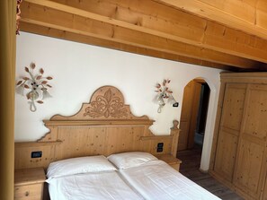 A wooden-framed bedroom with a large bed, two nightstands, and decorative wall sconces. - Double or Twin Room with Private Bathroom (Mestriago)