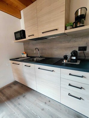 A kitchen with a microwave, sink, and coffee maker. - ABETE (Mestriago)