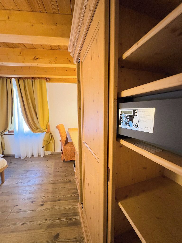 Een houten interieur met een bed, een stoel en een plank met een apparaat.