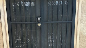 A black metal door with a keypad lock, a doormat with 'hello' on it, and a textured wall. - Private Spa Suite + Patio
The Tranquil Corner (Tucson)