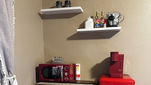 A kitchen with a microwave, a red refrigerator, and two shelves above containing kitchen items. - Private Spa Suite + Patio
The Tranquil Corner (Tucson)