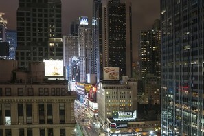 Eine beleuchtete Stadtlandschaft bei Nacht mit leuchtenden Werbetafeln und hohen Bürogebäuden.