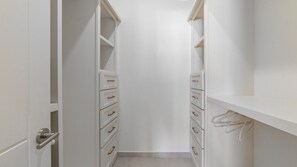 A narrow walk-in closet with white shelving and drawers, a door with a silver handle, and a visible cable on the right side. - Casa Rubi  5 bedroom home in the beachfront (Puerto Peñasco)