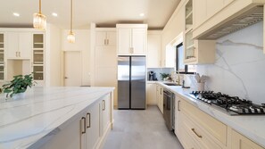 Uma cozinha moderna com ilha central, eletrodomésticos de aço inoxidável e painel de fundo de mármore.