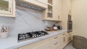 A modern kitchen with a gas stove, microwave, and oven. There are cabinets, a countertop, and a wicker basket. - Casa Rubi  5 bedroom home in the beachfront (Puerto Peñasco)