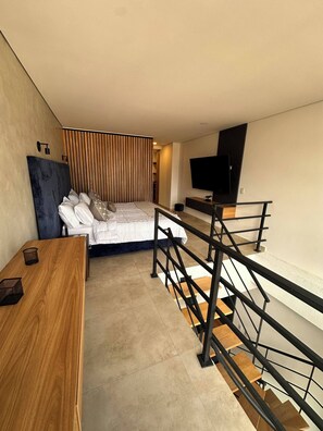 Ein Schlafzimmer mit einem Bett, einem Holztisch, einem Fernseher und einer Treppe.