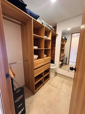 Ein Holzschrank mit mehreren Einlegeböden und Kleiderstange, einem Wäschekorb und einer Tür mit Schlüsselschloss.
