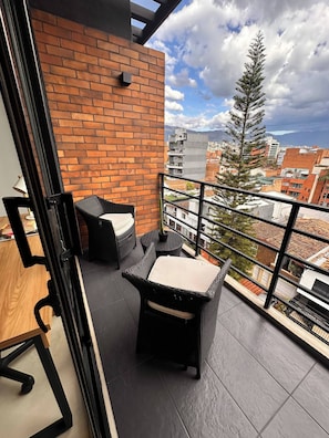 Een balkon met rieten meubilair en een bakstenen muur.