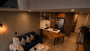 A modern interior with a sofa, coffee table, kitchen area, and staircase. - Duplex With Incredible View Rooftop Jacuzzi & GYM (Medellín)