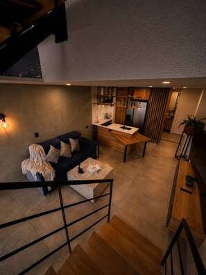 Ein modernes Interieur mit Sofa, Couchtisch, Küchenbereich und Treppe.