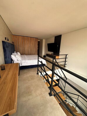 Een moderne hotelkamer met een bed, een bureau, een televisie en een trap.