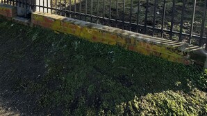 Un bâtiment entouré d’une clôture métallique, doté d’une petite fenêtre et d’une enseigne avec des chiffres.