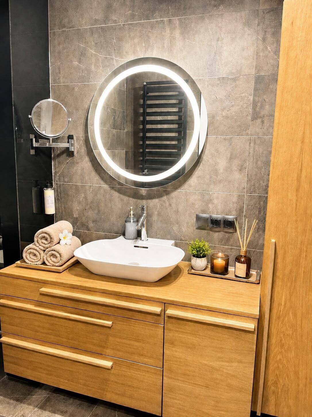 Un baño con un espejo redondo, un lavabo blanco y armarios de madera.