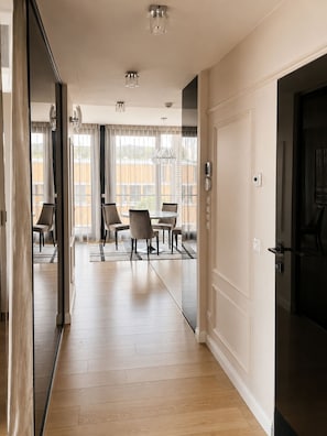 A hotel room with a wooden floor, a dining area with a round table and chairs, and a large window with curtains.