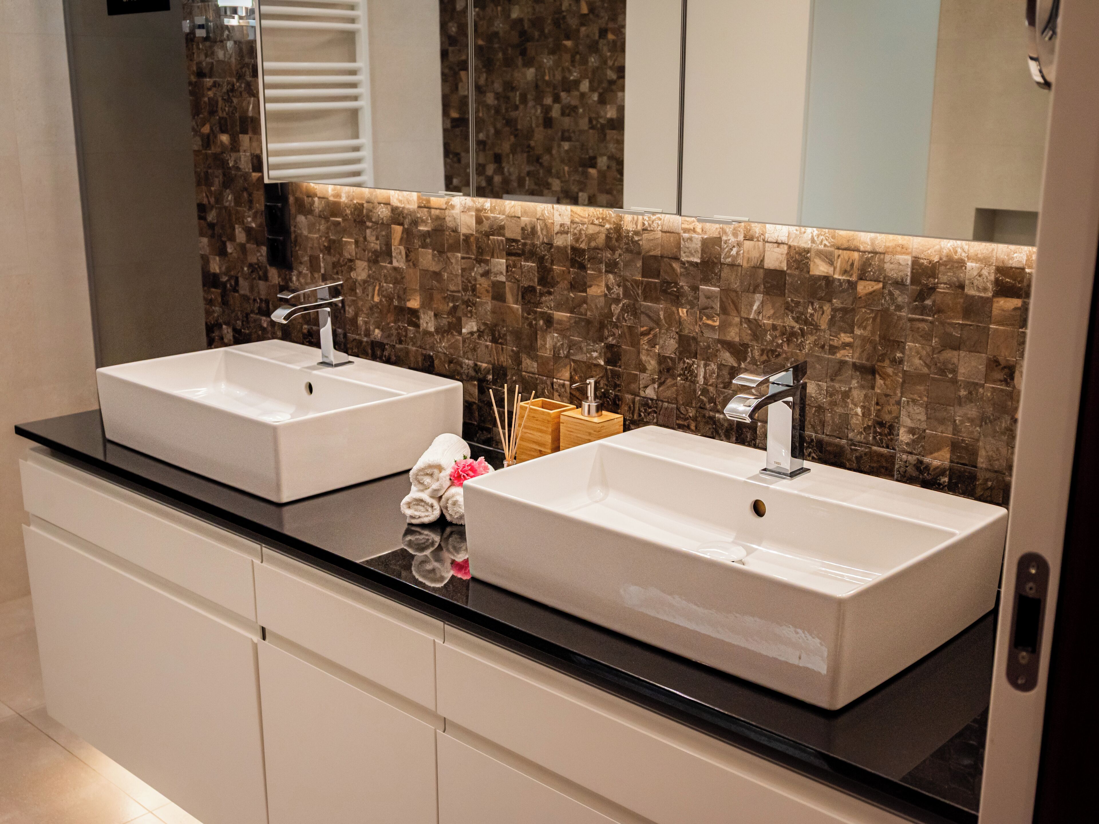 A bathroom with two sinks, a mirror, and a tiled backsplash.