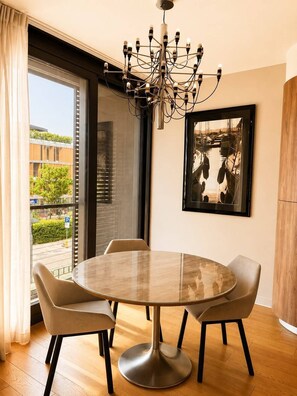 Un coin repas avec une table ronde, quatre chaises, un lustre et un tableau encadré au mur.