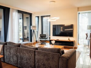 Un salon moderne doté d’un grand téléviseur à écran plat, d’un canapé, d’une table basse et d’un lampadaire.