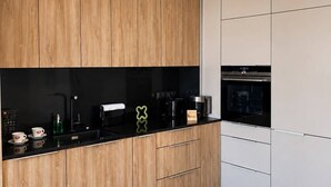Een moderne keuken met houten kastjes, een zwart aanrecht en een inbouwoven.