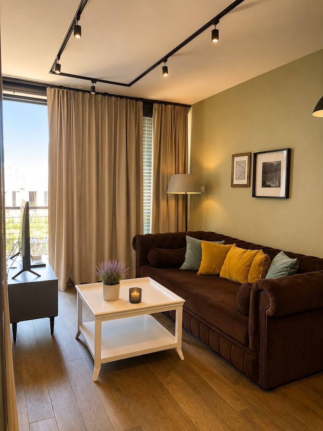 A modern living room with a brown sofa, a white coffee table, a lamp, and two framed pictures on the wall.